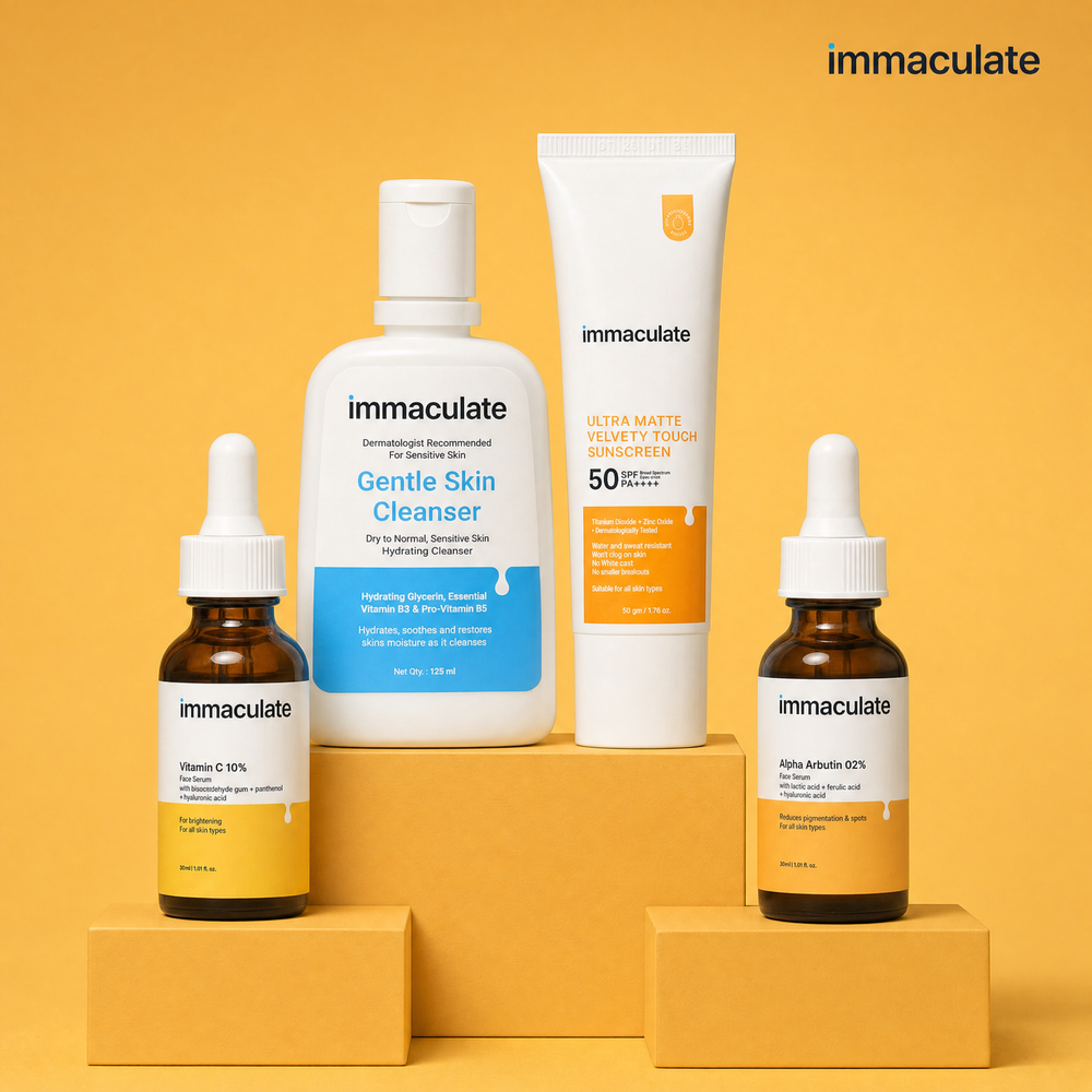 The Immaculate Dark Spot & Pigmentation Kit — cleanser, vitamin C serum, alpha arbutin serum and sunscreen on an amber studio set